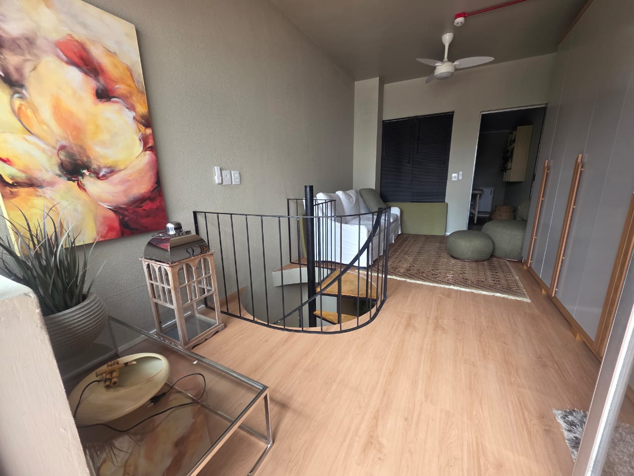 Sala 03 — sala interna com quadro abstrato floral e escada caracol