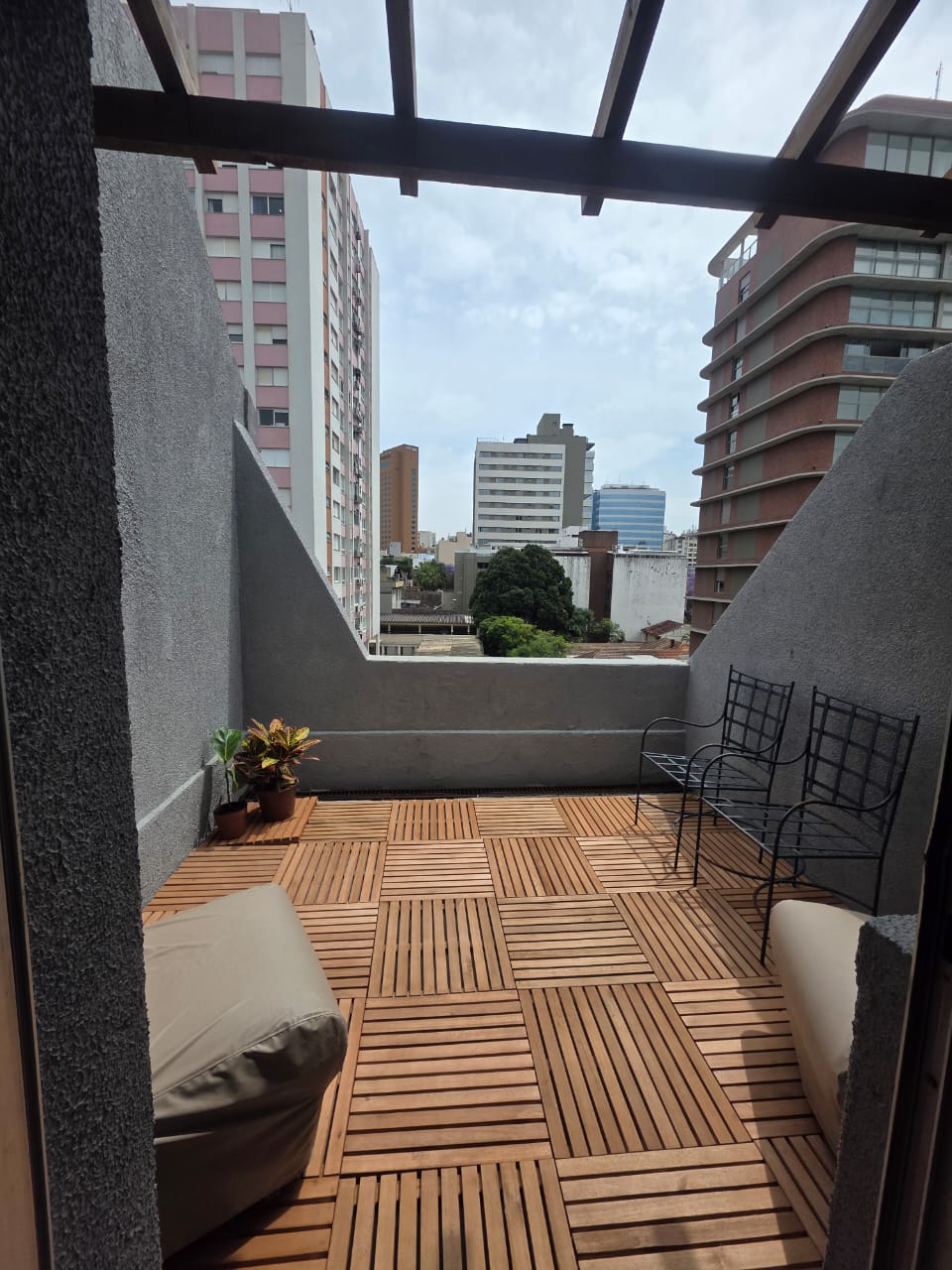 Sala 03 — terraço aberto da cobertura com pérgola de madeira e vista da cidade